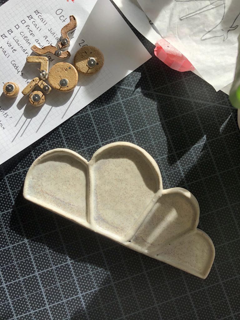 A ceramic palette next to a handful of ceramic earrings