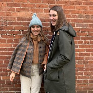 Elisenda and Kaila smiling and laughing in front of a brick wall