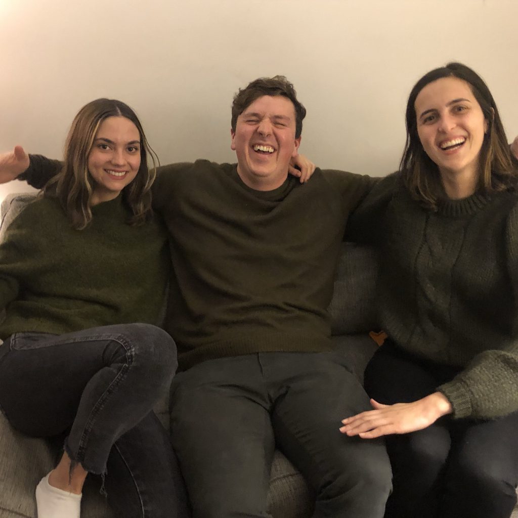 Three friends smile and laugh sitting on a couch