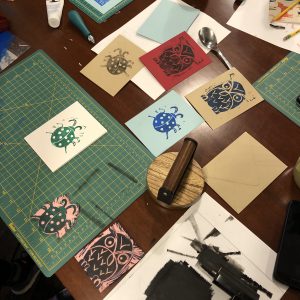 A table filled with creative mess and tools from block printing