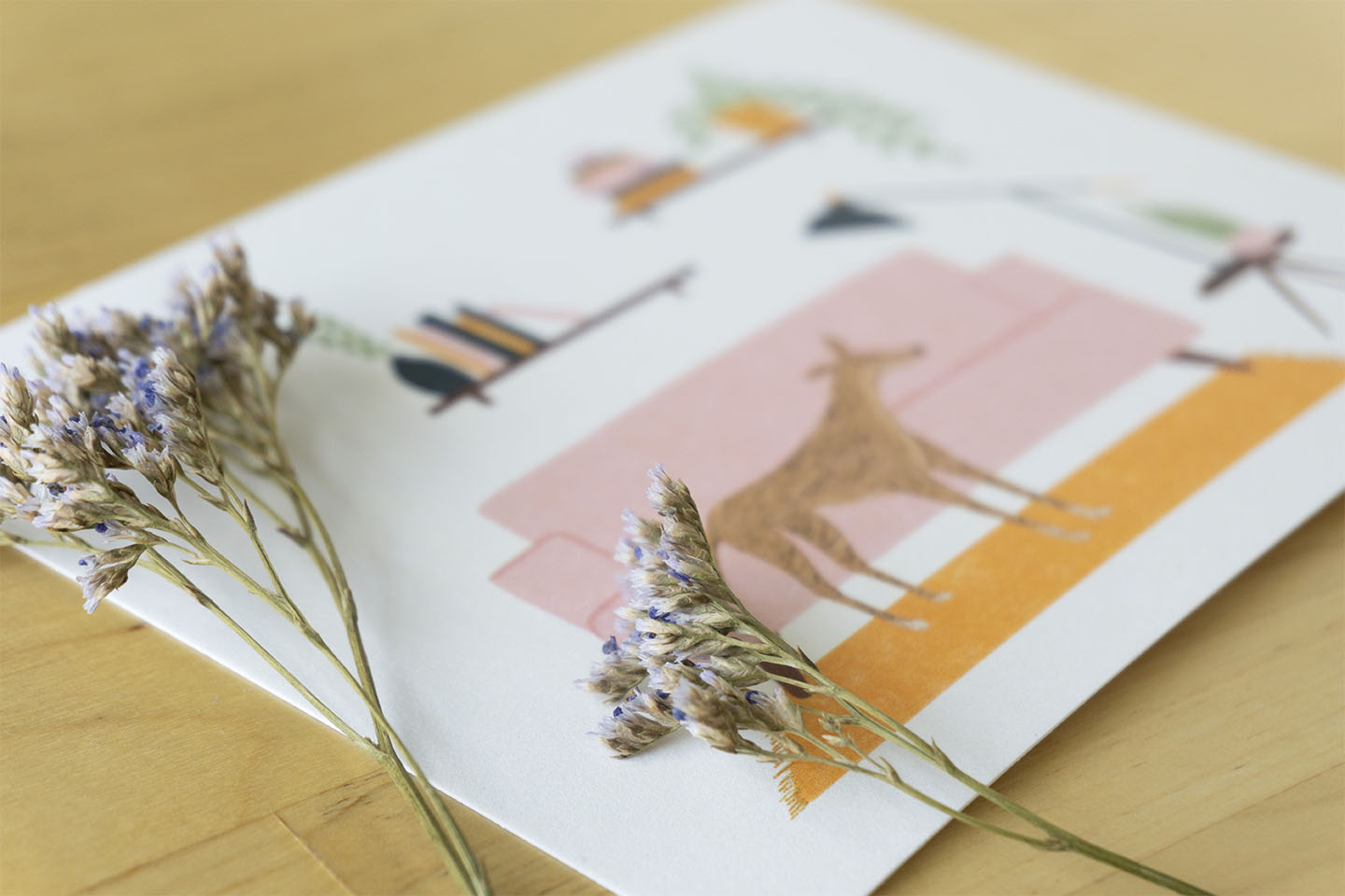 Two flowers rest on An art print of a greyhound napping in a living room