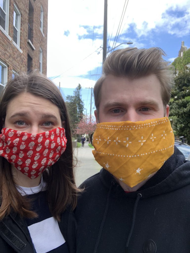 Kaila and Ian smile at the camera while wearing homemade face masks