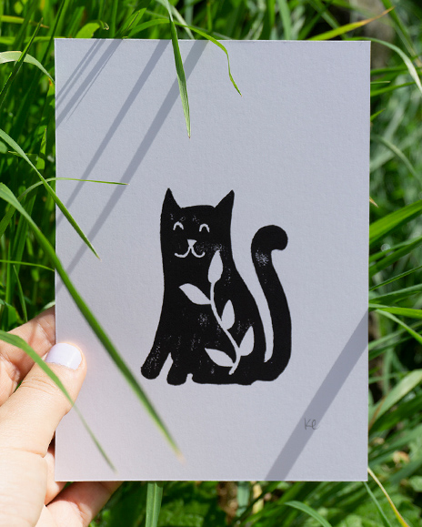 A linocut print of a cat with a leafy branch inside