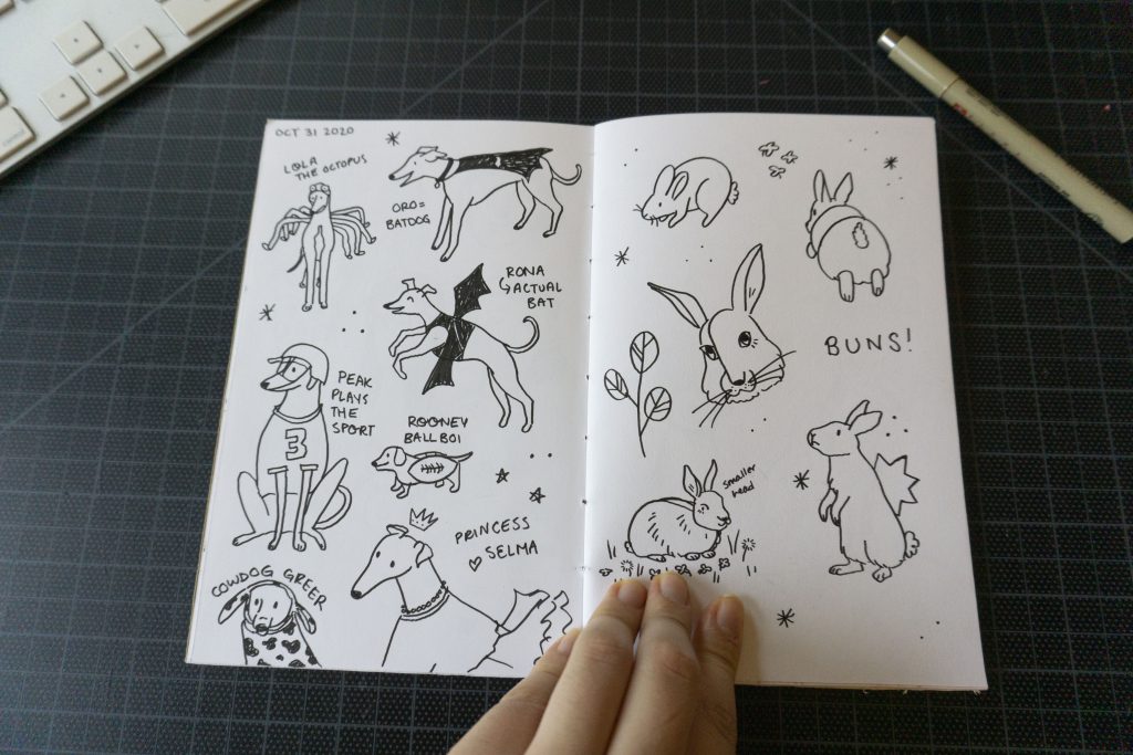 A sketchbook spread featuring illustrations of greyhounds in Halloween costumes and rabbits
